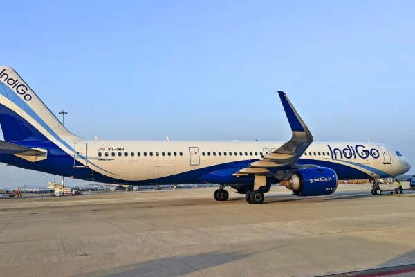 इंडिगो विमान के साथ हवाई अड्डे पर खड़े यात्री, बढ़े फ्यूल सरचार्ज का असर दिखाता दृश्य