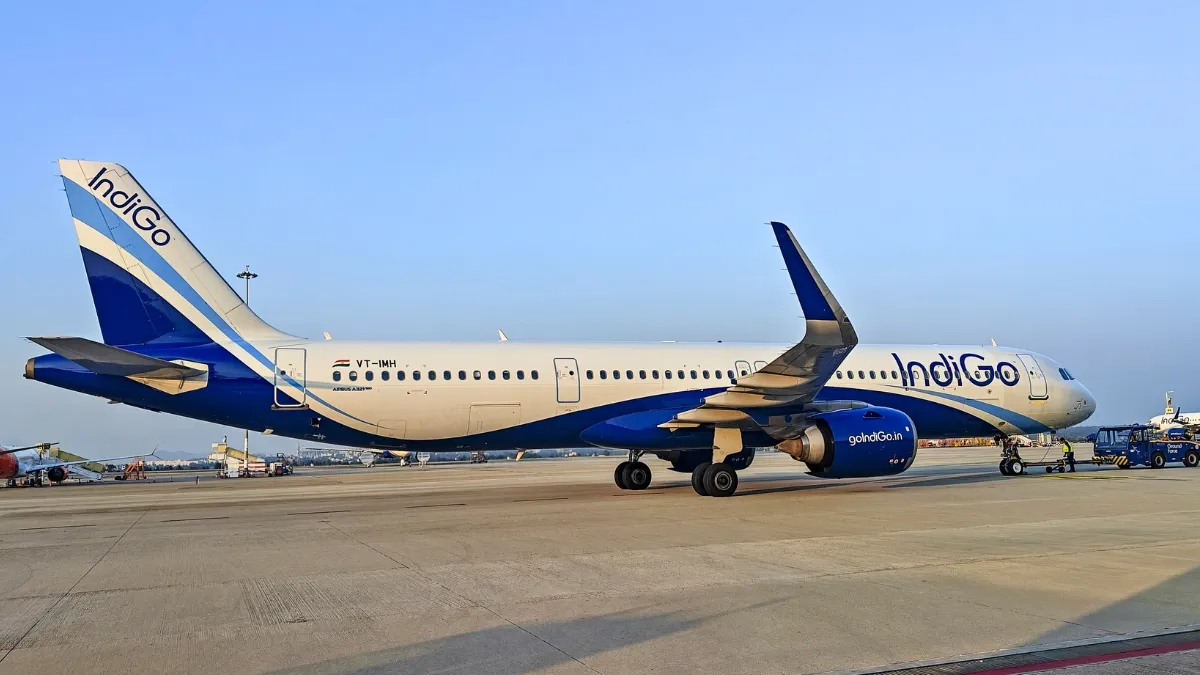 इंडिगो विमान के साथ हवाई अड्डे पर खड़े यात्री, बढ़े फ्यूल सरचार्ज का असर दिखाता दृश्य